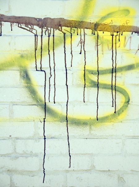 Detail of gang markings: paint driblets, like blood, on brick wall in alley