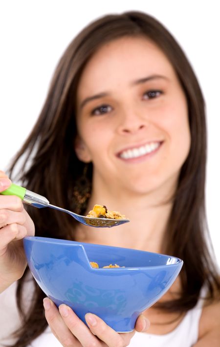 healthy girl eating cereal over a white background - focus is on the spoon with the cereal