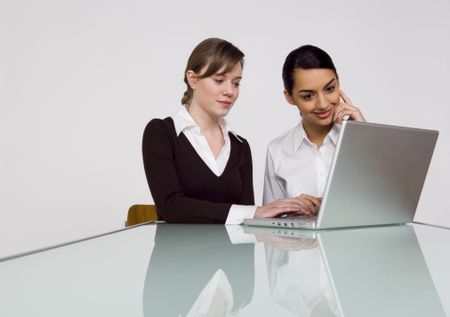 Two businesswoman working on a laptop.