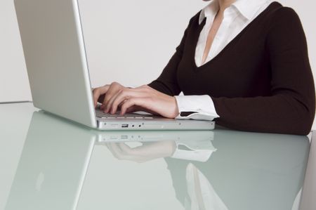 Close up of woman typing on a laptop at the office.