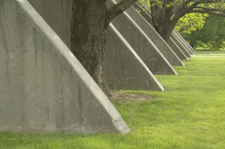 Series of concrete buttresses, with trees between two of them, outside athletic building on college campus