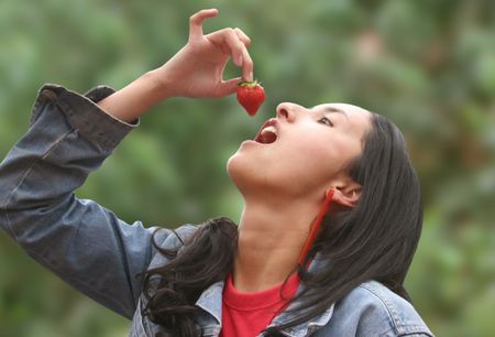 girl eating strawberry with trees in the background