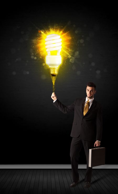 Businessman hold a shining eco-friendly idea bulb on a black background