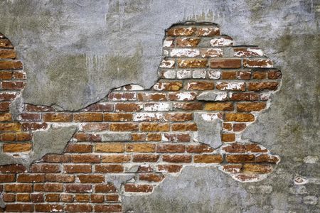 Vintage architectural grunge: Old brick exposed beneath thin concrete fallen off face of exterior wall