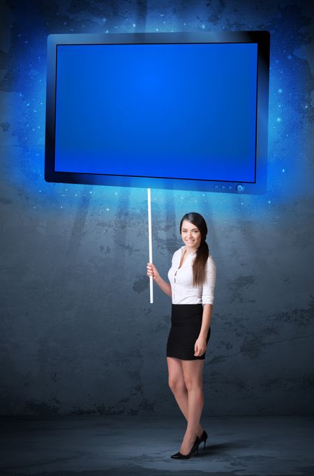 Young businesswoman holding a big, blue shining tablet

