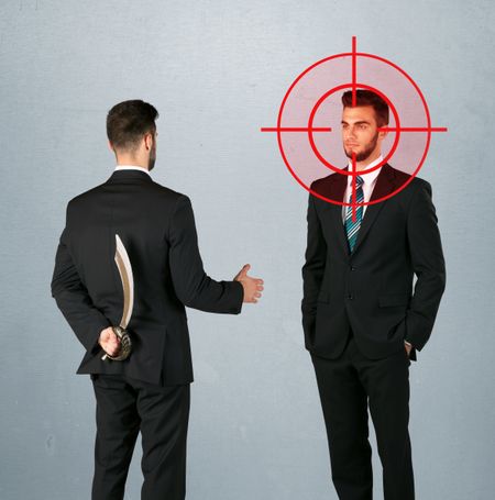 Ruthless businessman handshake with a hiding weapon and a head target point