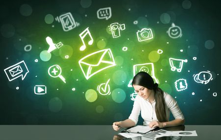 Businesswoman sitting at the black table with social media symbols on the background
