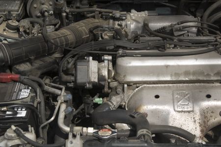Under the hood of a car: partial view of engine and battery, hoses, radiator, cables