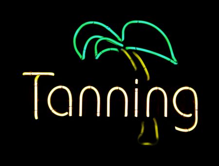 Neon sign in window of tanning salon, isolated on black