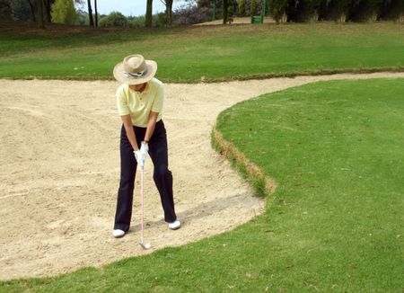 lady golfer trying to get out of the bunker
