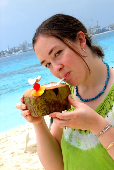 girl enjoying a cocktail with a nice blue beach in the background