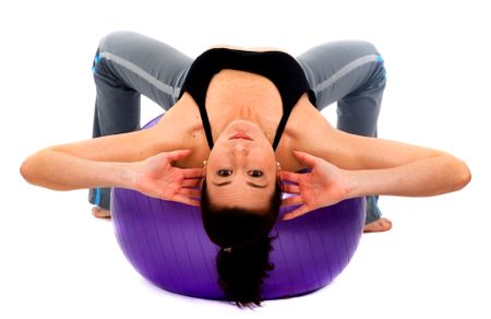 Beautiful girl doing abdominals on a pilates ball - isolated over a white background