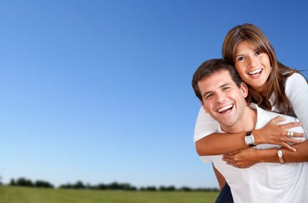 Beautiful couple smiling with a clear sky as the background