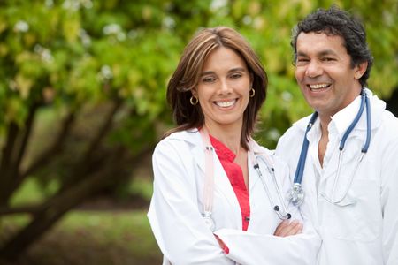 couple of doctors with stethoscopes smiling outdoors