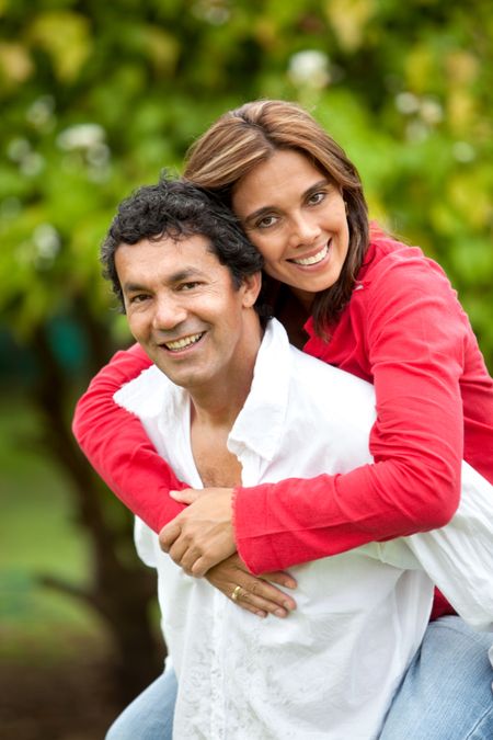 Man giving a piggyback ride to his wife outdoors