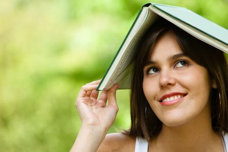 Thoughtful female student with a notebook on top of her head