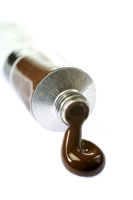 Brown paint coming from tube on white background