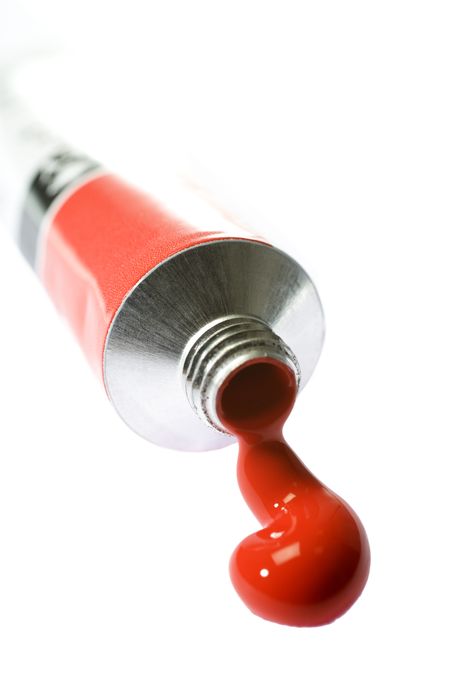 Red paint coming from tube on white background