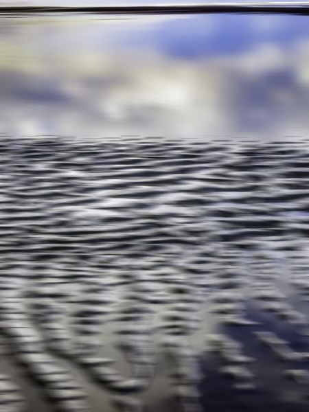 Abstract of rippled sandbar getting submerged in reflective tidal pool near edge of beach along Pacific coast of Olympic Peninsula in Washington, USA, for themes of nature, transience, the environment