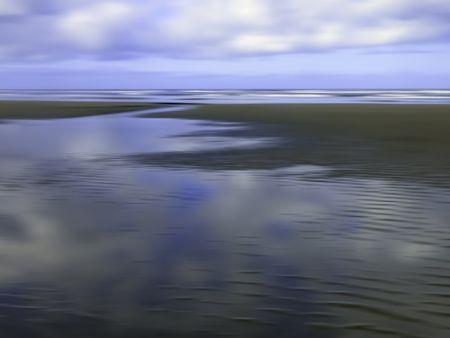 Serene morning abstract of large tide pool reflecting partly cloudy sky on sandy beach along Pacific coast of Olympic Peninsula in Washington, for themes of nature, transience, the environment