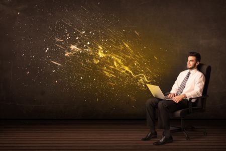 Businessman with laptop and energy explosion on background concept