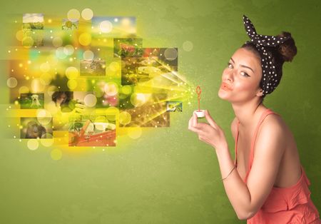 Cute girl blowing colourful glowing memory picture concept on green background