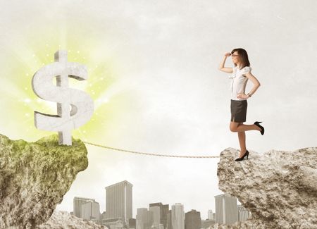 Businesswoman standing on the edge of mountain with a shining dollar mark on the other side 