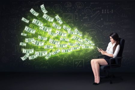 Businesswoman sitting in chair holding tablet with dollar bills coming out concept on background