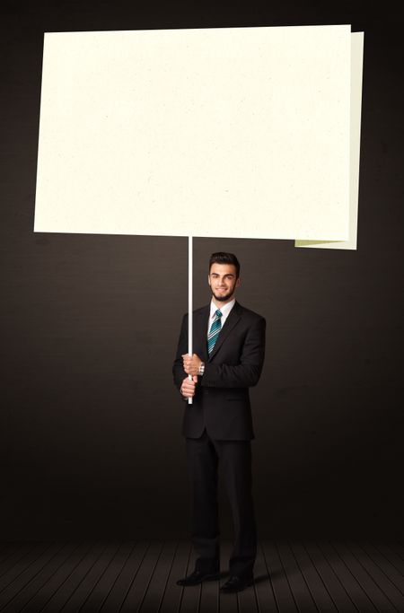 Young businessman holding a big, white post-it paper