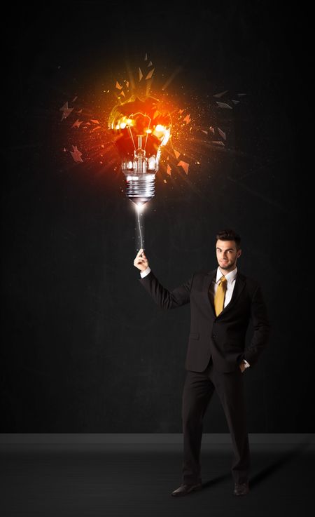 Businessman with an explosion bulb on black background