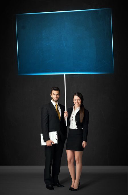 Young business couple holding a big, blue board 