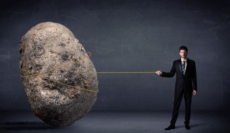 Businessman pulling huge rock with a rope concept on background