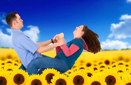 Beautiful couple having fun outdoors in a sunflower field - bright blue and yellow colours