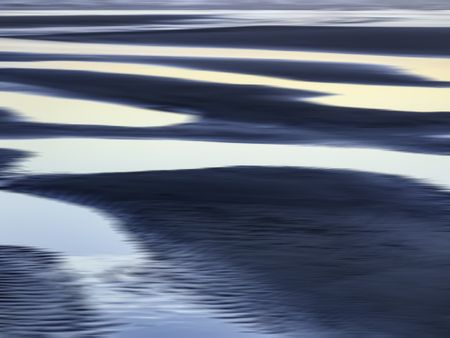Abstract of luminous tide pools on sandy beach at sunset along the Pacific coast of Olympic Peninsula in Washington, USA, for themes of nature, serenity, the environment (one of a series)