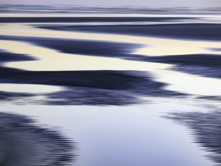 Abstract of luminous tide pools on sandy beach near sunset along the Pacific coast of Olympic Peninsula in Washington, USA, for themes of nature, serenity, the environment (one of a series)