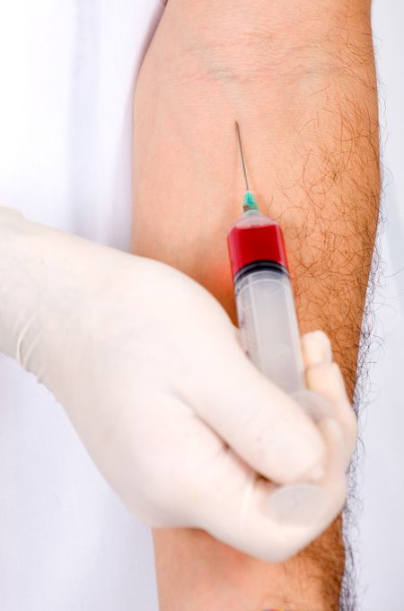 syringe taking out red blood from a male arm
