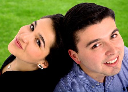 Beautiful couple smiling portrait - outdoors over a green grass background