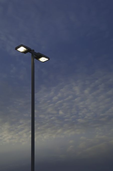 Two high outdoor lights against evening sky