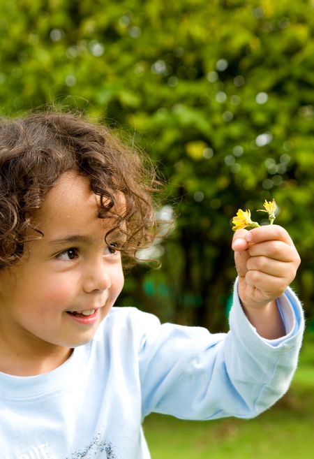 Child smiling while holding a flower outdoors