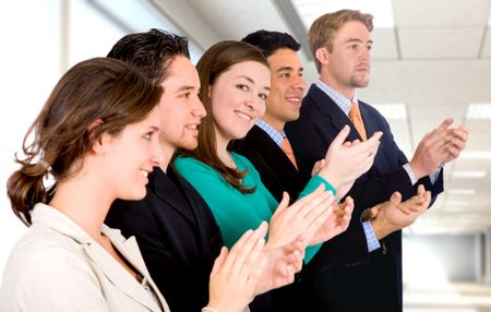 group of business people in an office applauding and smiling at success - Focus is on the girl looking at the camera