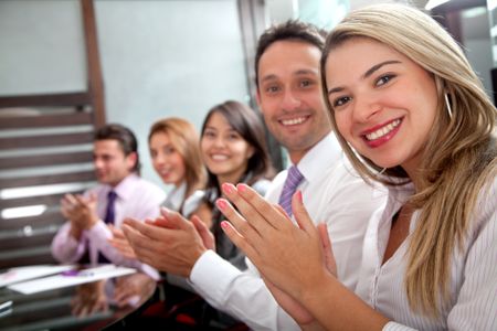 business team clapping in an office facing the camera