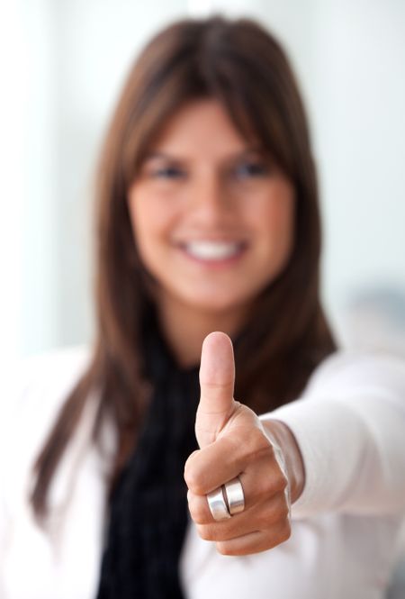 Thumbs up business woman smiling in an office