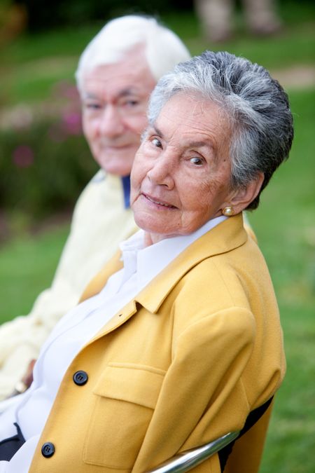 Beautiful elder couple sitting on a bench outdoors