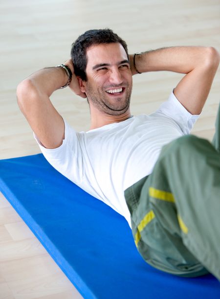 Happy man at the gym doing abdominals