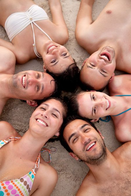 Friends at the beach with their heads together on the floor
