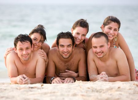 Group of friends at the beach lying on the sand