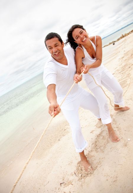 Beach couple making an effort pulling a rope