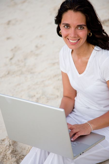 Working woman at the beach smiling with a laptop