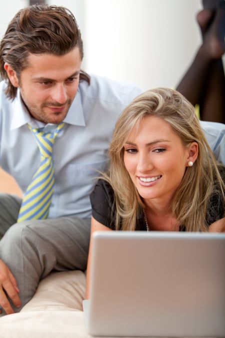 Business couple working with a laptop smiling
