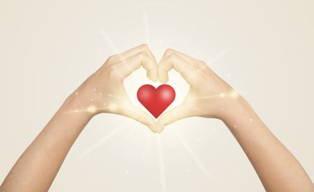 Hands creating a form with shining red heart in the center